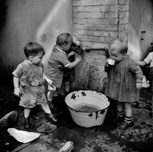 823240 Afbeelding van peuters uit de kindercrêche, die rond een teil met water aan het spelen zijn, op de binnenplaats ...